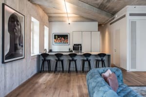 A modern living room with concrete flooring and a blue tufted sofa.