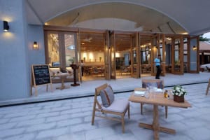 Modern restaurant interior with wooden furniture and open doors to dining area