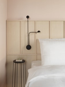 A minimalist bedroom featuring a wood-paneled wall and a bed with white bedding.
