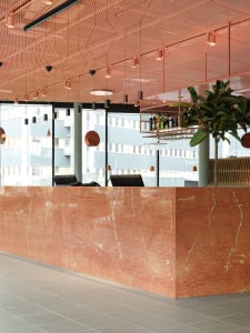 Modern restaurant interior featuring a polished marble counter with seating and decorative elements.