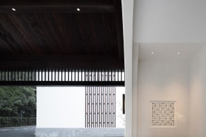 A minimalist entryway featuring wooden cabinets with geometric patterns, concrete walls, and paper lanterns.