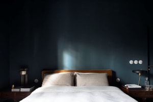 A minimalist bedroom with a white bed and blue accent wall