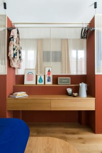 Modern closet with wood shelves, a functional desk, and a hanging space with perforated metal panels.