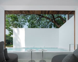 A minimalist poolside lounge featuring concrete walls and a small pool.