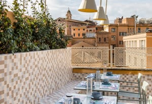 Outdoor seating area with tiled walls, concrete patio, greenery, and urban cityscape view.