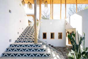 A minimalist staircase entryway with black and white geometric tile flooring and a wooden railing.