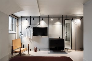 A minimalist clothing rack made of metal, featuring hangers and a mirror.