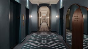 A modern hotel hallway featuring a patterned carpet and wooden accents.