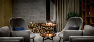 A modern living room with a fireplace, wooden accents, and concrete walls.