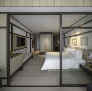Modern minimalist bedroom suite featuring a king-sized bed with white bedding, stylish decor, and sleek furniture.