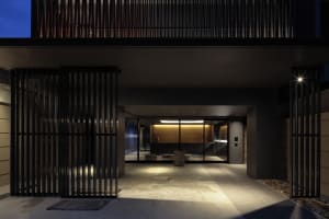 A modern, geometric entrance featuring metal gates and concrete flooring at dusk.