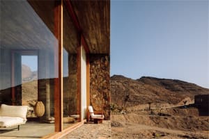 Modern exterior residential building with concrete walls and large windows overlooking rugged mountains.