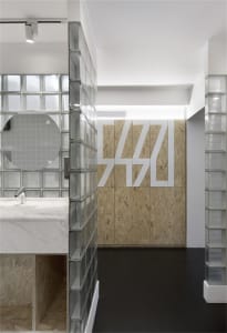A modern industrial office interior designed with glass blocks, OSB panels, and marble.