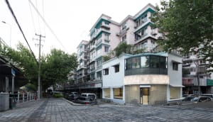 A street view of urban architecture featuring windows, plant balconies, and various building materials.
