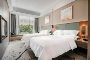 Modern minimalist hotel room with white textiles and green accent colors.