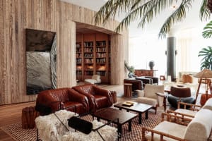 A modern living room featuring leather sofas, wooden walls, and upholstered chairs.