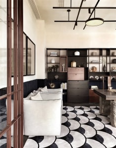 Modern living room with white couch, black and white patterned rug, and black bookshelf with various decorative items.