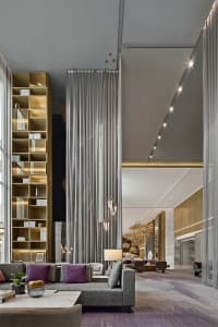 Modern lounge area with contemporary furniture, high ceilings, and large windows.