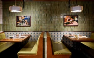 Restaurant interior with green tile walls and wooden tables with white tablecloths