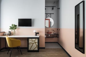 A modern, minimalist workstation featuring a sleek desk, a yellow chair, and a flat-screen TV.