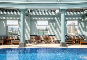 Roof top pool area featuring concrete pillars, tiled walls, and glass windows
