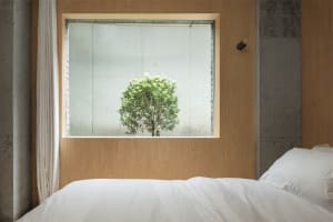 A minimalist bedroom with a concrete accent wall and a bed.