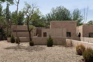 A modern house with stucco exterior and surrounding greenery.