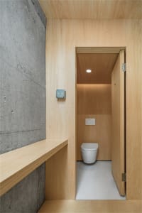 A modern bathroom with wood-paneled walls and a concrete floor.