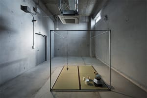 A minimalist industrial-style room with a metal-framed structure containing a tatami mat setup.