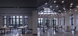 Modern industrial restaurant interior featuring metallic finishes, glass elements, and concrete surfaces.