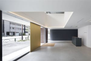 Modern hotel entry featuring gold accents, brick, concrete, and a black wall.