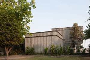 A modern architectural structure with a concrete exterior surrounded by greenery.