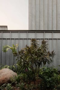 Modern building exterior with metal cladding and lush greenery.