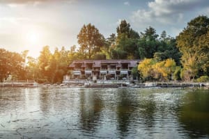 A traditional architectural building situated by a tranquil lake surrounded by lush greenery and trees.