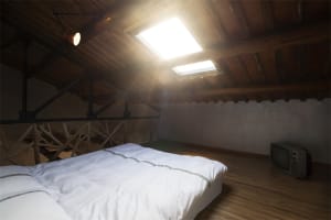 An industrial-style bedroom with wooden walls and a slanted wooden ceiling.