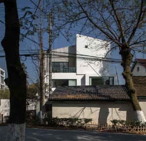 A modern house with a white concrete exterior and large windows.