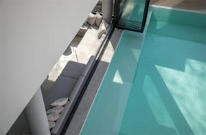 A modern glass swimming pool area with a relaxation lounge adjacent to it.