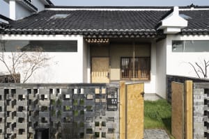 Boarded-up front door of a traditional residential exterior with tiled roof and white walls.