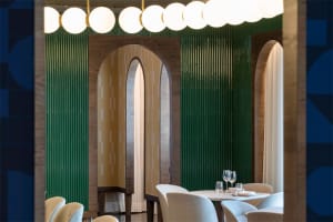 Modern restaurant interior featuring wood, curved glass, and green tiles.