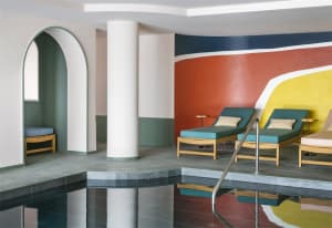 A modern spa interior featuring concrete flooring, colorful walls, and teal lounge chairs.