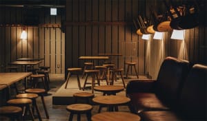 An industrial-style bar area with wooden stools and tables in an open-plan layout.
