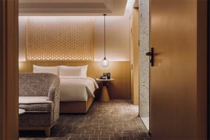 A modern hotel bedroom with a wooden accent wall and a neatly made bed.