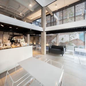 A modern industrial coffee shop with white concrete walls, white furniture, and a sleek design.