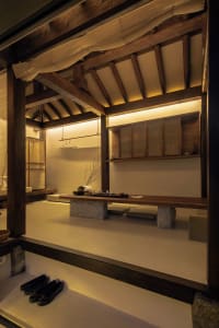 Traditional Japanese tea room featuring a wooden table, seating, and floral decoration.