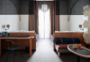 A modern bedroom interior featuring wooden furniture, cotton bedding, and iron accents.