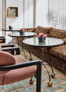 Modern living room featuring a patterned sofa, glass tables, and floral arrangements.