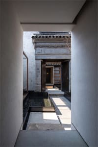 An elegant entrance path made of concrete with a water feature and stone slabs.