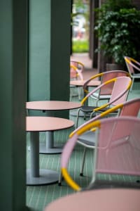 Pink and yellow metallic frame chairs and tables in a modern restaurant setting.