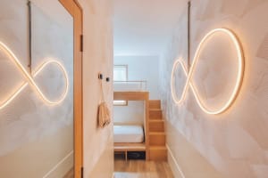 Minimalist bedroom with wooden bunk bed, metallic railing, and textiles.