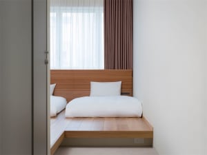 A minimalist bedroom featuring wooden flooring and a simple, uncluttered design.